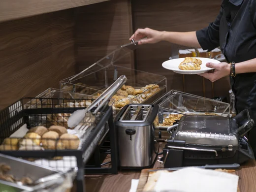Boutique Hotel a Verona · Touring 3★ · A 2 min da Piazza Erbe Persona che prende un cornetto da un buffet con tostapane e piastra