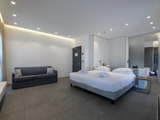 Boutique Hotel a Verona · Touring 3★ · A 2 min da Piazza Erbe Camera d'albergo moderna con letto matrimoniale e divano grigio