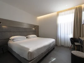 Boutique Hotel a Verona · Touring 3★ · A 2 min da Piazza Erbe Camera d'albergo moderna con letto matrimoniale, scrivania e finestra con tende