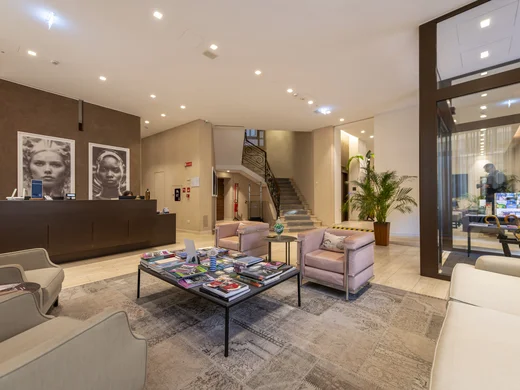 Boutique Hotel a Verona · Touring 3★ · A 2 min da Piazza Erbe Reception di hotel con divani, tavolino e due grandi ritratti in bianco e nero