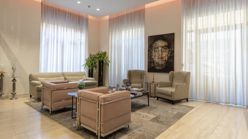 Boutique Hotel a Verona · Touring 3★ · A 2 min da Piazza Erbe Salotto moderno con poltrone, divano beige e grande quadro in una stanza luminosa