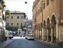 Boutique Hotel a Verona · Touring 3★ · A 2 min da Piazza Erbe Strada con portici e archi in mattoni in una città italiana soleggiata